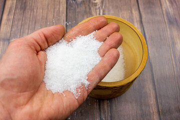Seasoning salt. Salt is natural. Salt in a wooden box. Salt and hands.