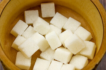 Sugar cubes. White refined sugar. Sugar cubes in a wooden box. Sugar and hands.