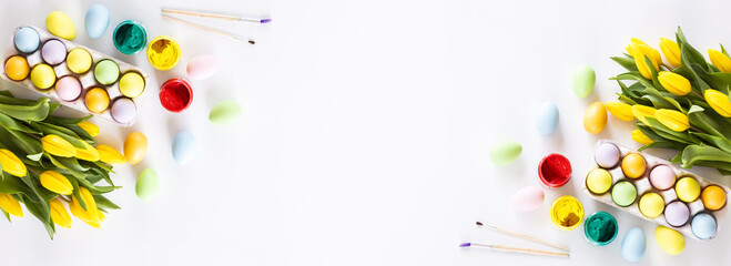 Stylish background with colorful easter eggs isolated on white background with yellow tulip flowers. Flat lay, top view, mockup, overhead, template