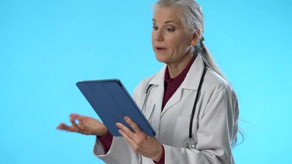Happy female doctor with tablet computer isolated on blue background with copy space.