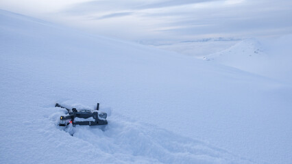 Fototapeta na wymiar Drone crashed in the snow high up on a mountain