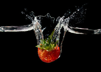 Red strawberry in water splash on black background.
