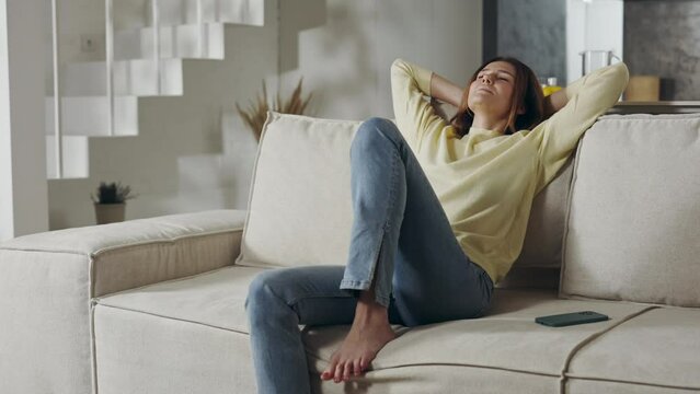 Happy woman in casual wear resting on sofa at home