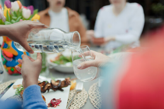 Close up man pouring water from carafe at patio table