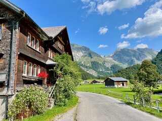 Fototapeta na wymiar Typical wooden houses in Toggenburg, Alpstein range in the background. St. Gallen, Switzerland.