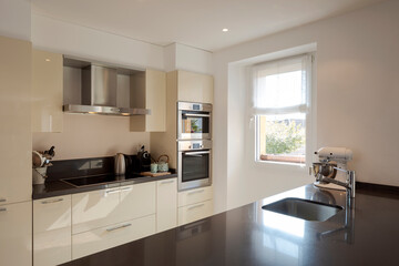 Modern kitchen detail with large dark island with stools. Stainless steel sink.