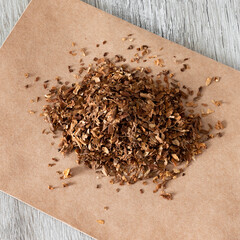 A square photo of dried sliced tobacco or a smoking drug mixture. Smoking drugs on paper close-up...