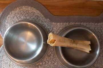 Overhead view of a dog chew bone in metal bowl.