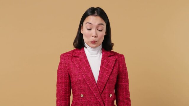 Fun confused shy shamed young woman of Asian ethnicity 20s wears red jacket looking camera spreading hands say oops ouch oh omg i am so sorry isolated on plain pastel beige background studio portrait