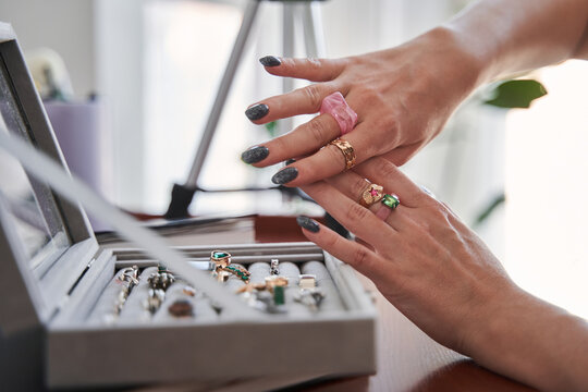 Stylish caucasian woman sitting in front of the opened cassette and trying on different rings