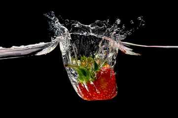 Red strawberry in water splash on black background.