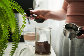 Woman holding spoon with coffee and putting it into the jar while preparing morning hot drink