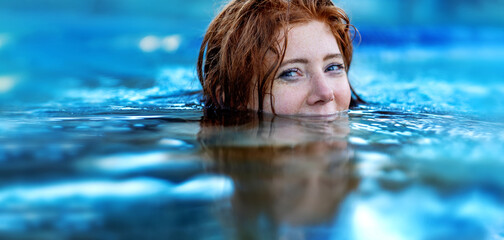 Pretty sexy, seductive, sensual redhead woman portrait relaxes swimming in turquoise, blue thermal...