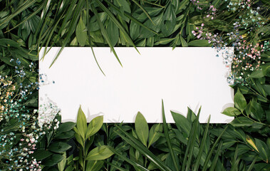 Creative layout made of flowers and  green leaves with white paper card note. Flat lay. Nature concept background.