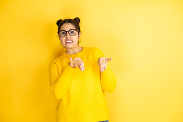 Young beautiful woman wearing casual sweater over isolated yellow background disgusted expression, displeased and fearful doing disgust face because aversion reaction.Annoying concept - obrazy, fototapety, plakaty
