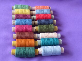 Spools of thread of different colors are stacked in a row. Multicolored threads for sewing.