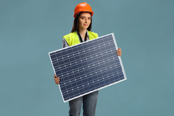 Female construction worker holding a photovoltaic solar panel