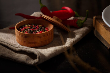 Red hot chilli pepper and dry pepper assortment in spice pot on sack, kitchen table background, contrast light. Spices, flavourings for food.