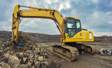Excavator with a hydraulic hammer in an andesite quarry. Powerful crawler machine