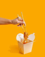 wok noodles in paper box fast food yellow background