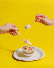Women's hands take dessert with dessert spoons. fast food. yellow background