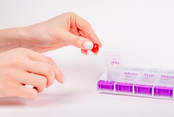 Woman hands taking pill or vitamin from organizer. Daily health treatment and medication concept....