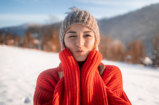 Love winter pretty girl blowing a kiss on snowy field