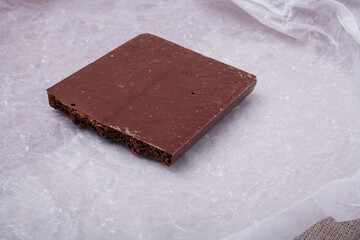 Porous chocolate bar on white paper. Bubbled or spongy chocolate, tasty sweets, carbohydrate food,...