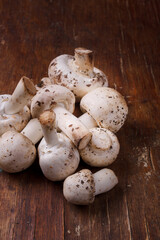 Fresh champignons on wooden table. Seasonal ogranic healthy food, ketogenic diet. Mushrooms on rustic background. Close up vertical shot, close up.