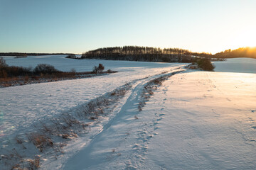 Aerial drone view of a road on winter snow covered fields at sunset