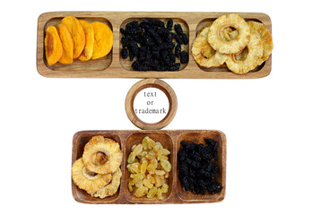 Dried fruits on wooden plates. Dried peach, mulberry, raisin and pineapple. Between them is a plate with space for text or a trademark. Isolated on white background.