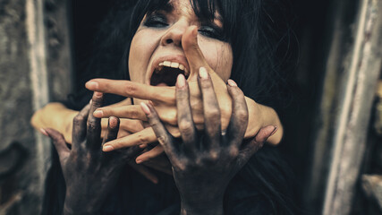 Emotional woman witch in black strangling hands she shouts