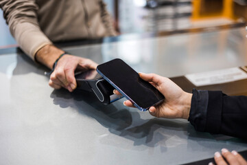 Woman paying contactless with mobile phone in shop