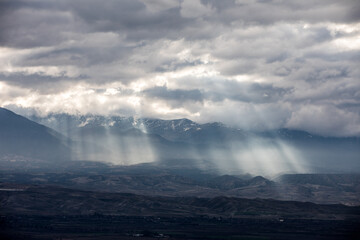 Sun light piercing through the clouds and hitting the mountains