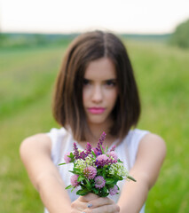 Fototapeta premium Young woman offering bouquet of spring flowers. Focus is on flowers. 
