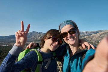 A Teenage boy with braces and mother taking selfie during hiking in nature