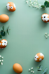 Frame of Easter eggs and flowers on pastel green background. Happy Easter vertical banner mockup....