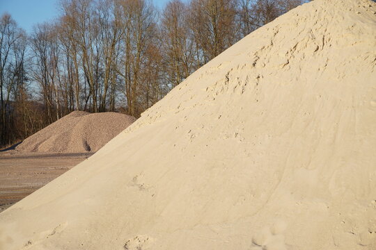 Sandberge vor Baumlandschaft und Himmel bei Abendsonne im Winter