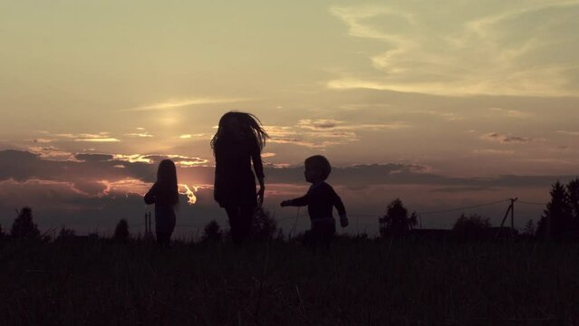 happy children and mother run across the field. Sunset, Dawn