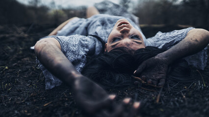 a witch with black hands lies on the ground that has burned