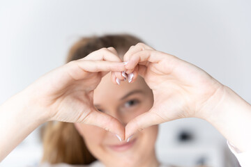 Blonde teenager making love or heart sign with hands