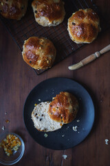 Close up flat lay Easter theme food image shot from above. Freshly baked and served on a plate hot cross buns. Ingredients and baking utensils in shot. Copy space available. Dark and vintage style