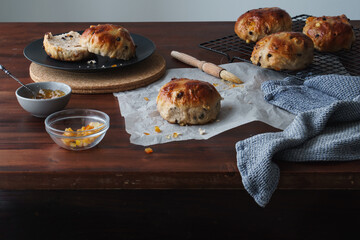 Kitchen table food image of traditional Easter treats. Freshly baked hot cross buns. Baking equipment and ingredients included in frame. Copy space available