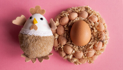 Obraz na płótnie Canvas Toy chicken with eggs in the nest on pink background.