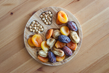 Dried fruits and roasted chickpeas in wooden plate. Dried palm dates, figs and apricots.