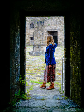 blonde young woman with blue coat taking photos at Castillo de San Felipe. Stone and earth coastal castle from the 16th century with views of the Ferrol estuary