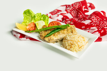 Grilled Sea Bass with rice and Greek salad in a dish isolated on colorful table cloth top view on grey background