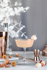 Fototapeta na wymiar Pink Lychee Cocktail. Champagne coupe glass filled with pink lychee cocktail or mocktails surrounded by ingredients and bar tools