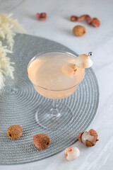 Pink Lychee Cocktail. Champagne coupe glass filled with pink lychee cocktail or mocktails surrounded by ingredients and bar tools