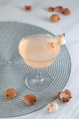 Pink Lychee Cocktail. Champagne coupe glass filled with pink lychee cocktail or mocktails surrounded by ingredients and bar tools